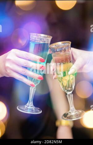 Zwei Frauenhänden mit Gläsern Champagner auf festlichem Hintergrund. Stockfoto