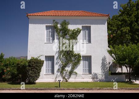 Weiß getünchtes Haus mit vier Fenstern und Weinpflanze an der Fassade, Griechenland Stockfoto