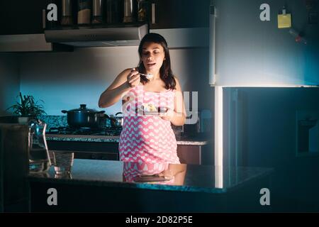 Lateinamerikanische Schwangere Frau Essen In Der Nacht Stockfoto