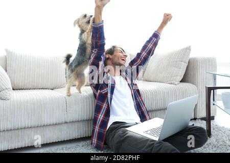 Happy Guy frohlockt mit seinem Hund sitzt in der Nähe der Couch im Wohnzimmer. Stockfoto