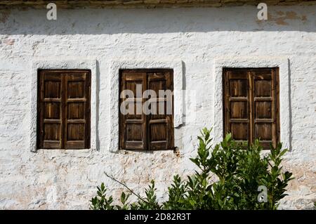 Drei Holzfenster an der weißen Wand eines griechischen Hauses Stockfoto