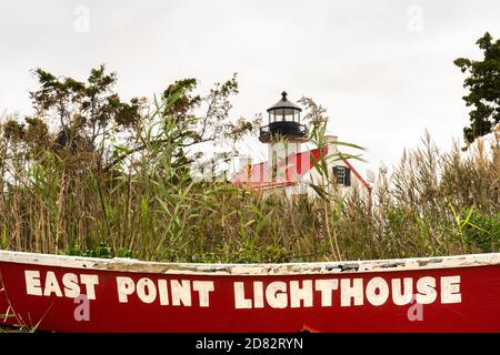 Der Name des East Point Lighthouse ist bemalt Ein rotes Ruderboot im Vordergrund mit dem Leuchtturm in Der Hintergrund teilweise von Gräsern verdeckt Stockfoto