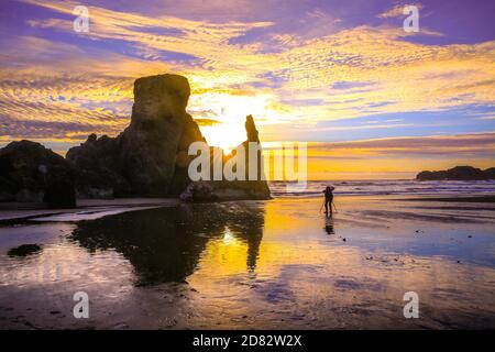 Professionelle Fotografin fotografiert Felsformationen und den Sonnenuntergang am Bandon Beach, Oregon-USA Stockfoto