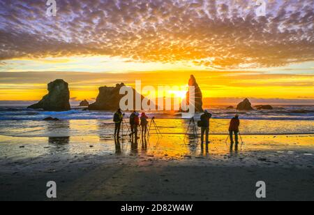 Gruppe von Fotografen, die Fotos von Felsformationen und Sonnenuntergang am Bandon Beach, Oregon-USA, machen Stockfoto