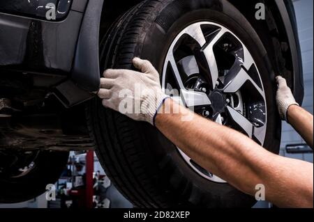 Nahaufnahme des Mechanikers entfernt ein Rad aus dem Auto Stockfoto