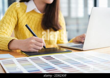 Grafikdesigner, der mit Farbmustern zur Auswahl arbeitet. Grafikdesigner bei der Arbeit. Farbmuster. Junge Fotografin und Grafikdesignerin bei Stockfoto