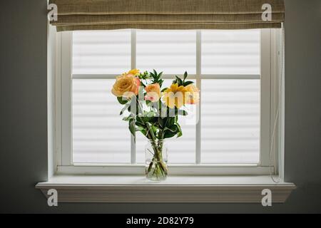 Gelber Blumenstrauß im Einmachglas auf Fensterbank Stockfoto