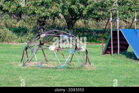 Verrostete alte Spielgeräte, wie diese gewölbte Affenriegel und Rutsche, sind noch n Einsatz auf diesem kleinen Spielplatz in Michigan USA Stockfoto