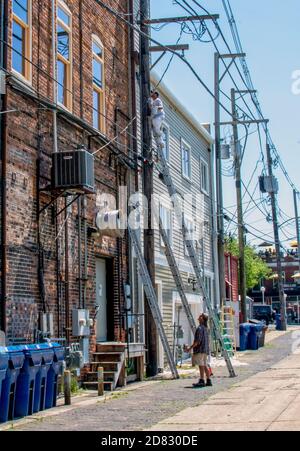 St Joseph MI USA June 12 2020; Arbeiter auf einer hohen Leiter repariert ein Gebäude in einer Innenstadt, während ein Mitarbeiter für Sicherheit steht Stockfoto