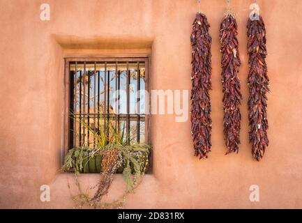 Chili-Pfeffer-Ristras und eiserne Gitterfenster; Altstadt von Albuquerque, New Mexico. Stockfoto