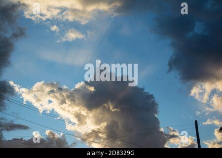 Strahlen des Sonnenlichts, die durch die Wolken strahlen wie riesige Lichtscharten, die durch den Himmel schneiden, blauer Himmel, himmlisch Stockfoto