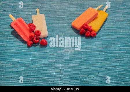 Fruchtpopsicles auf einem aquabluen Hintergrund im Sommer einschließlich Wassermelone Popsicle, tropische Frucht Popsicle, Mango Popsicle, und Limettenpopsicle mit Fr. Stockfoto