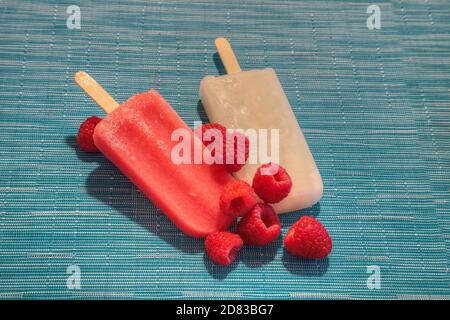 Fruchtpopsicles auf einem aquabluen Hintergrund im Sommer einschließlich Wassermelone Popsicle, tropische Frucht Popsicle, Mango Popsicle, und Limettenpopsicle mit Fr. Stockfoto