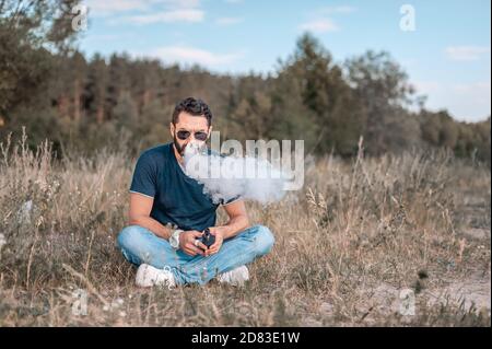 Stylish brutal vape Mann Ausatmen Dampf aus elektronischen Zigarette in der frischen Luft. Moderne Wege, Tabak zu beenden. Stockfoto