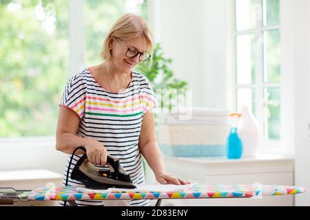 Frau bügelt Kleidung. Weibliche Klamotten am Bügelbrett. Hausarbeiten. Hausfrau Reinigung Haus. Stockfoto