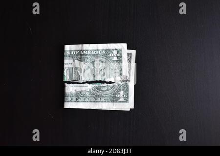 Zerrissen gerissen entwertet ein Dollar Banknote auf einem schwarzen Hintergrund. Nahaufnahme von schlechtem Geld. Der Zusammenbruch des Dollars. Abwertung. Sinkende Währung. Stockfoto
