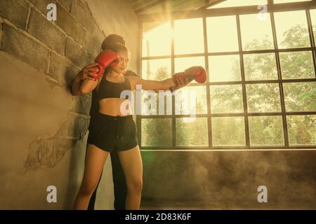 Herrentrainer mit Boxerin und orangefarbenem Licht im Hintergrund. Stockfoto