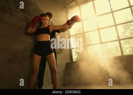 Herrentrainer mit Boxerin und orangefarbenem Licht im Hintergrund. Stockfoto