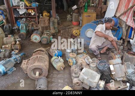 Ein Mann in Chor Bazar / Bazaar (Thieves' Market) in Mumbai, Indien, arbeitet an alten Motoren, um nutzbare Teile zu verkaufen Stockfoto