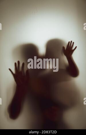 Konzept Schatten von Mutter und Kind küssen das matte Glas Verschwommener Hand- und Körperfokus Stockfoto