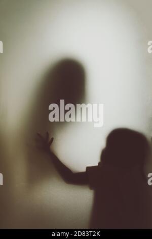 Geist Konzept Schatten der Mutter, die den Hals strangling Des Kindes hinter dem matten Glas verschwommen Hand und Weicher Körperfokus Stockfoto