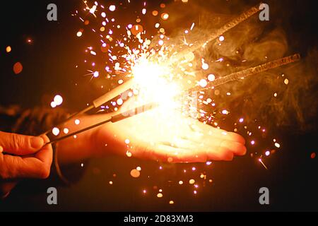 Funken und Licht von Wunderkerzen im Dunkeln auf der Handfläche einer Person. Weihnachtszauber, Silvester, festlicher Hintergrund. Leerzeichen für Text Stockfoto