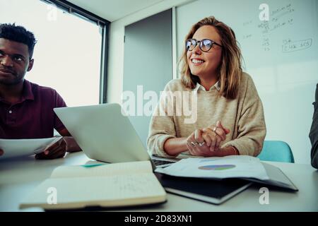 Nahaufnahme weibliche Geschäftsfrau lächelnd Genehmigung der Ideen präsentiert von Kollege, der während des Geschäftsmeetings mit dem Team um den Tisch sitzt Stockfoto