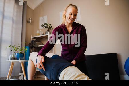 Nahaufnahme des Physiotherapeuten, der die Ausrichtung der Brückenposition korrigiert studio Stockfoto