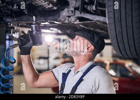 Handsome Auto Mechaniker mit Schlagschrauber in der Garage Stockfoto