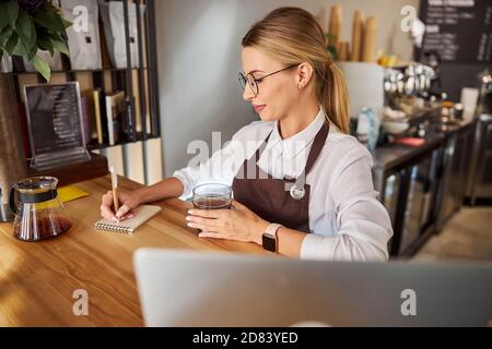 Charmante Verkäuferin in Gläsern am Holzschreibtisch Stockfoto