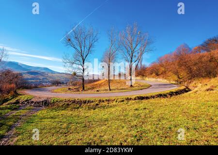 Landstraße im Herbst. Morgenlandschaft in gebirgiger ländlicher Umgebung. Bäume im Herbstlaub auf dem Pass. Helles sonniges Wetter Stockfoto