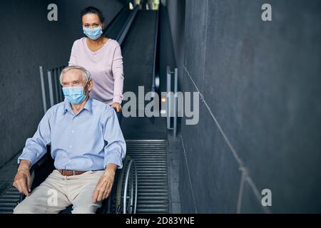 Junge Frau hilft für alten Mann zu gehen die Rolltreppe Stockfoto