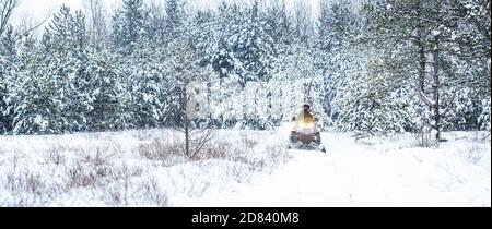 Sportler fährt ein Schneemobil in den Bergen. Schneemobil im Schnee. Konzept Wintersport. Ein Mann fährt Schneemobil in den Bergen. Pilot auf einer Sportart Stockfoto