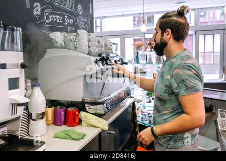 Junger Kellner, der die Kaffeemaschine zubereitete Stockfoto