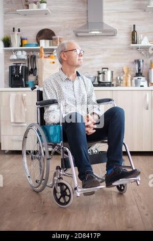 Behinderter älterer Mann im Rollstuhl fühlt sich einsam und schaut auf das Fenster. Ältere behinderte Rentner nach Verletzung und Reha, Lähmung und Behinderung für depressive ungültig voller Trauer, Sorge und trauriges Gesicht. Renteneintrittszeit für alte Menschen Stockfoto