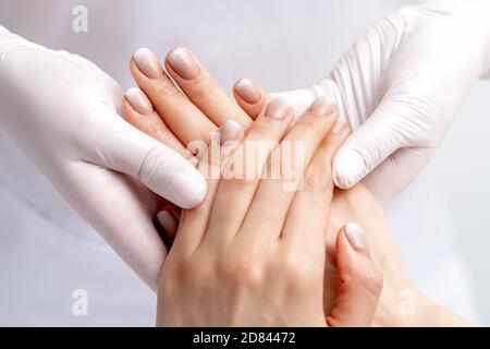 Manikurist trägt Handschuhe dabei Wachs Massage auf weiblichen Händen mit Maniküre im Nagelstudio Stockfoto