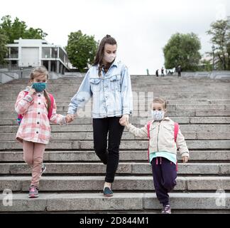 Zurück in die Schule . Coronavirus pandemische Kinder gehen in Masken zur Schule. Freundliche Beziehungen zu meiner Mutter. Stockfoto