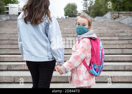 Zurück in die Schule . Coronavirus pandemische Kinder gehen in Masken zur Schule. Freundliche Beziehungen zu meiner Mutter. Stockfoto