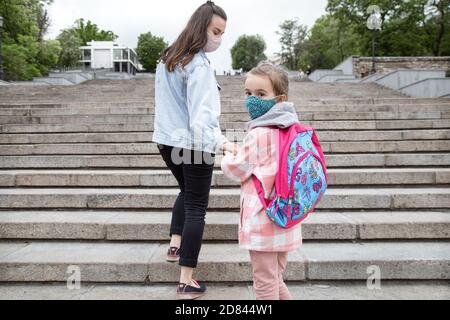 Zurück in die Schule . Coronavirus pandemische Kinder gehen in Masken zur Schule. Freundliche Beziehungen zu meiner Mutter. Stockfoto