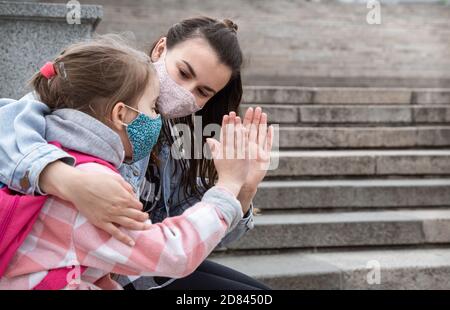 Zurück in die Schule . Coronavirus pandemische Kinder gehen in Masken zur Schule. Freundliche Beziehungen zu meiner Mutter. Stockfoto