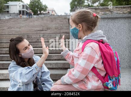 Zurück in die Schule . Coronavirus pandemische Kinder gehen in Masken zur Schule. Freundliche Beziehungen zu meiner Mutter. Stockfoto