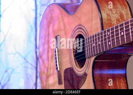 Akustische Gitarre auf einem schönen farbigen Hintergrund. Das Konzept der Saiteninstrumente. Nahaufnahme. Stockfoto