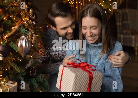 Lächelnder Mann Gruß aufgeregt Frau präsentiert Weihnachtsgeschenk Stockfoto