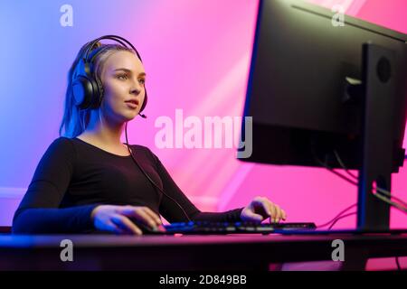 Fokussierte Gamer Girl mit Headset spielen Online-Video-Spiel auf PC Stockfoto