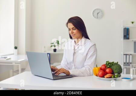 Ernährungsberater mit Laptop machen Diät-Plan oder Beratung zu geben Kunden online Stockfoto