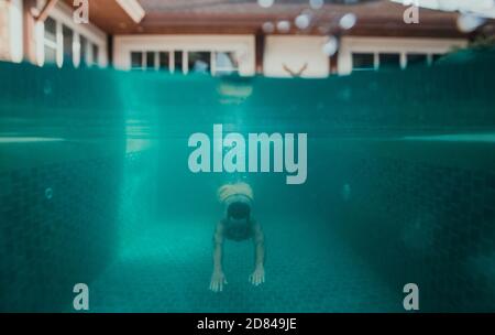 Mann schwimmend im Pool unter Wasser, in seinem schönen Ferienhaus Stockfoto