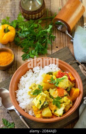 Indische Küche Gericht Sabji. Traditioneller indischer Gemüseeintopf mit Weichkäse, Kurkuma und Reis auf einem Holztisch. Stockfoto