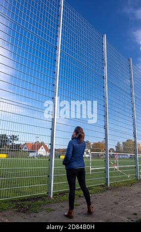 Schwerin, Deutschland. Oktober 2020. Eine Frau steht vor einem Lärmschutzzaun auf einer Seite des Sportfeldes des Sportvereins Neumühler. Die Vereinigung der Steuerzahler hat den Zaun als Beispiel für die Verschwendung von Steuergeldern in ihrem Black Book 2020/21 veröffentlicht. Quelle: Jens Büttner/dpa-Zentralbild/dpa/Alamy Live News Stockfoto