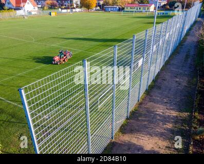 Schwerin, Deutschland. Oktober 2020. Auf einer Seite des Sportfeldes des Sportvereins Neumühler steht ein Lärmschutzzaun, während im Hintergrund die Wiese gemäht wird (Luftaufnahme mit Drohne). Die Vereinigung der Steuerzahler hat den Zaun als Beispiel für die Verschwendung von Steuergeldern in ihrem Black Book 2020/21 veröffentlicht. Quelle: Jens Büttner/dpa-Zentralbild/dpa/Alamy Live News Stockfoto