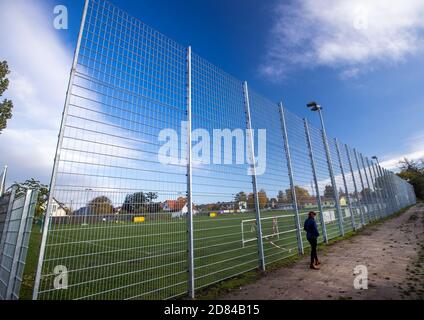 Schwerin, Deutschland. Oktober 2020. Eine Frau steht vor einem Lärmschutzzaun auf einer Seite des Sportfeldes des Sportvereins Neumühler. Die Vereinigung der Steuerzahler hat den Zaun als Beispiel für die Verschwendung von Steuergeldern in ihrem Black Book 2020/21 veröffentlicht. Quelle: Jens Büttner/dpa-Zentralbild/dpa/Alamy Live News Stockfoto